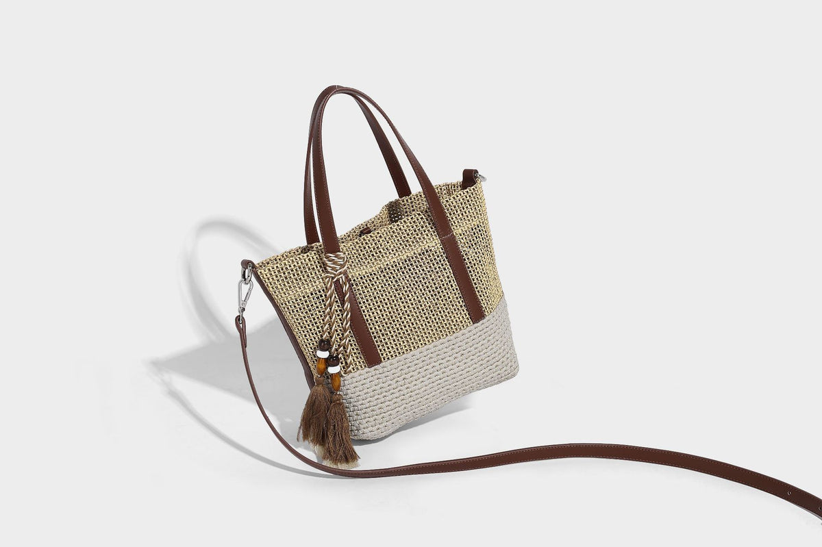 Two-tone open-weave tote bag in beige and cream with brown leather-look handles, tassel bead charm, and detachable