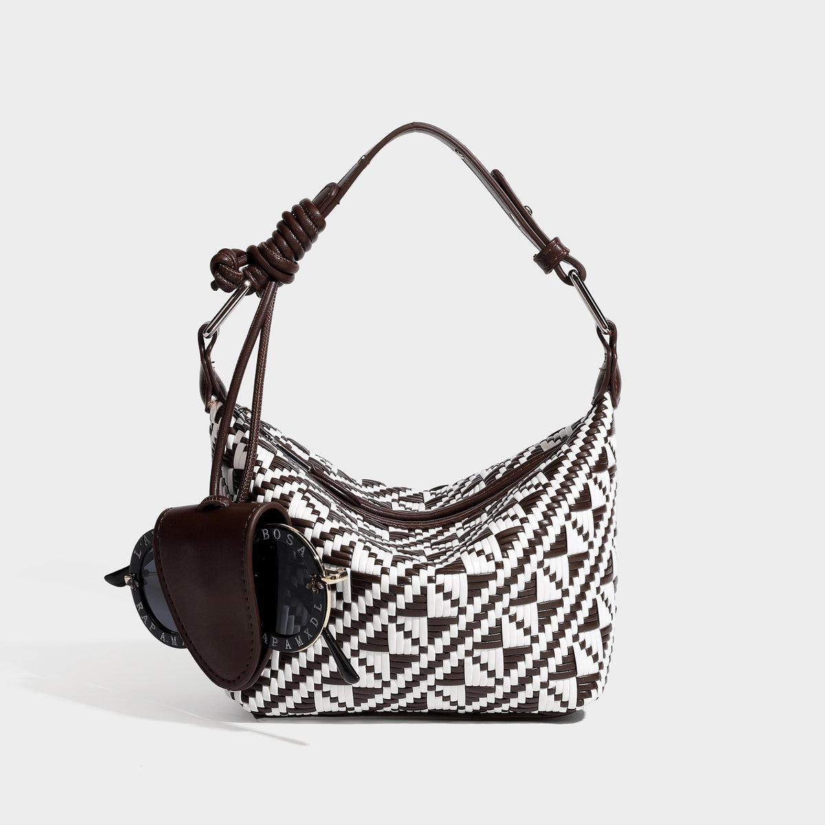 Kleine gewebte Schultertasche mit geometrischem Schwarz-Weiß-Muster, glatter dunkelbrauner Einfassung in Lederoptik, geknotetem verstellbarem Riemen, seitlicher