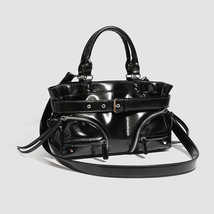 Black glossy structured tote bag with rivet and buckle detail, dual top handles, and detachable shoulder strap, detail view 2