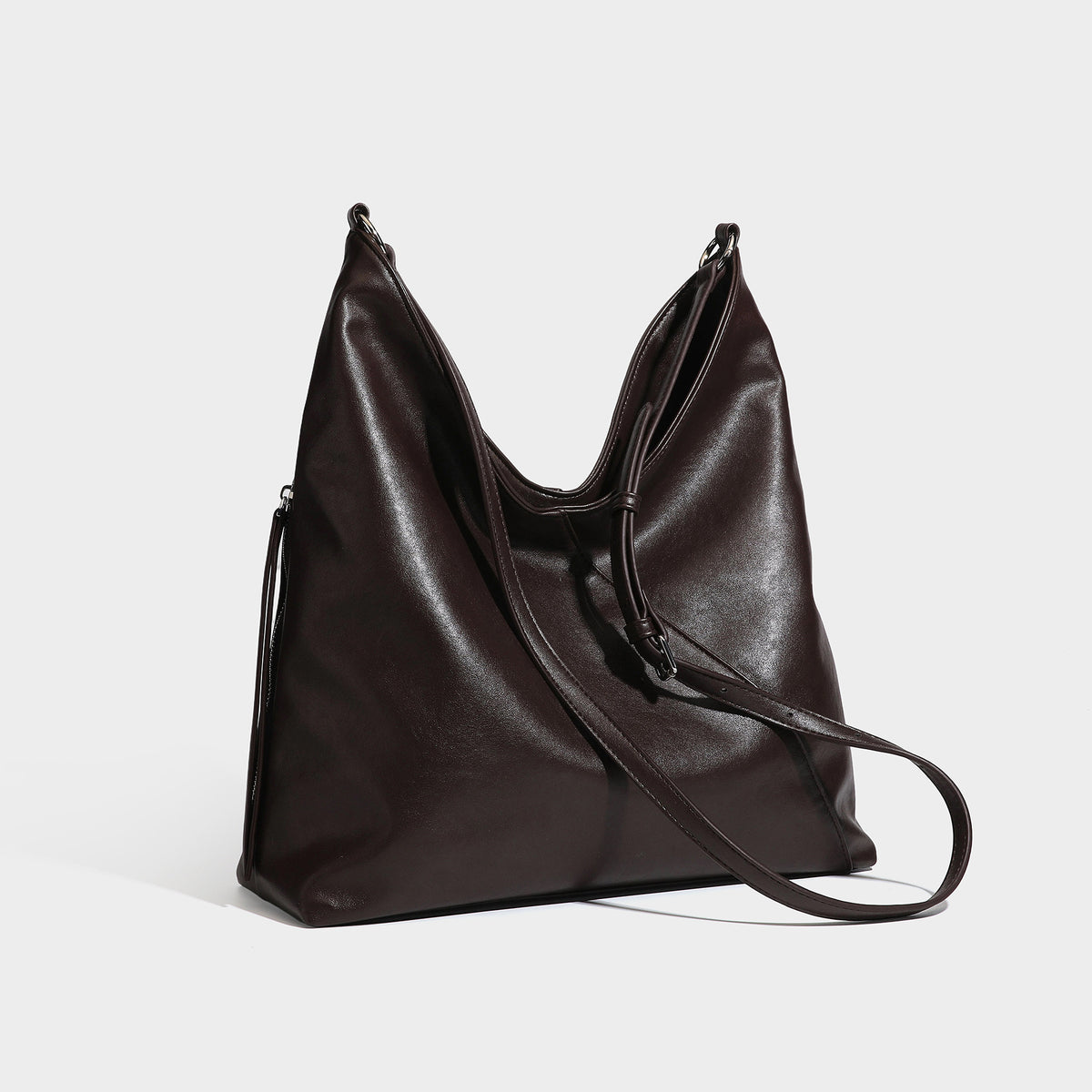 Large slouchy hobo shoulder bag with braided top handle, smooth glossy leather-look finish, and silver-tone ring hardware