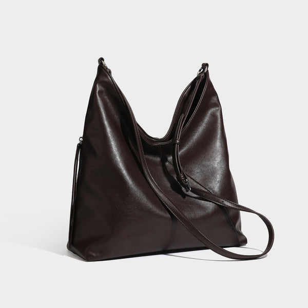 Large slouchy hobo shoulder bag with braided top handle, smooth glossy leather-look finish, and silver-tone ring hardware