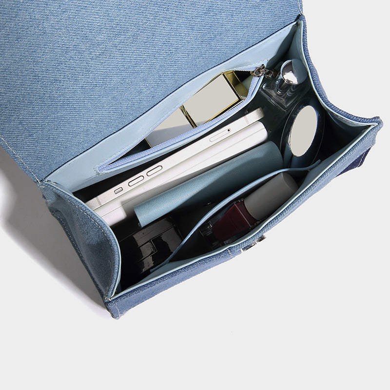 Structured patchwork denim trapezoid satchel bag with frayed panel trim, rounded top handle, and silver-tone hardware, detail