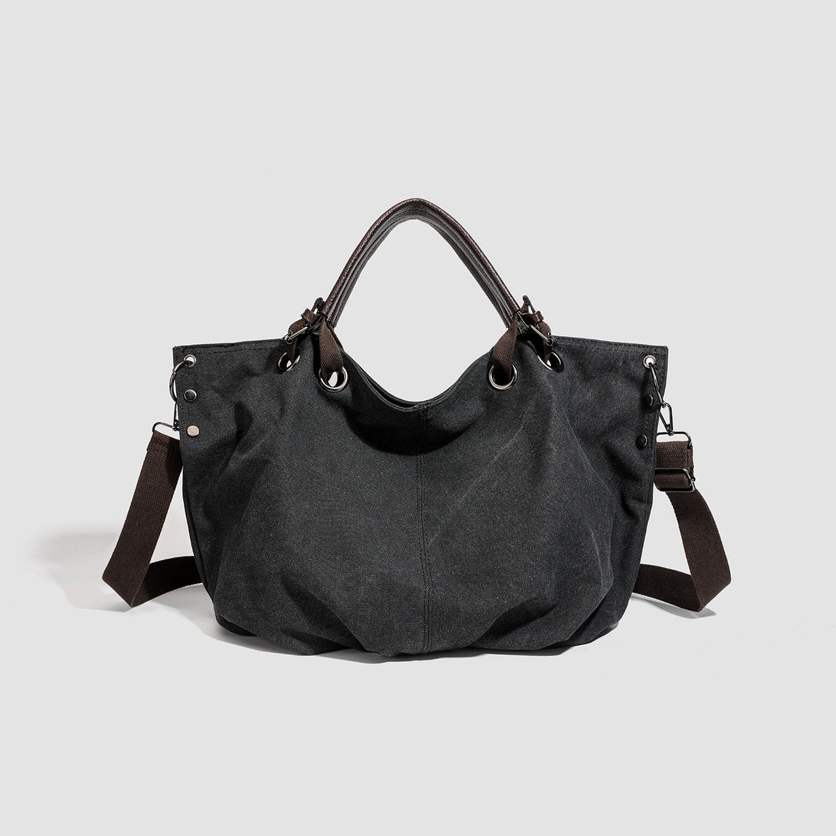 Slouchy matte canvas tote bag with dark dual top handles, metal grommet hardware, and detachable long shoulder strap, detail