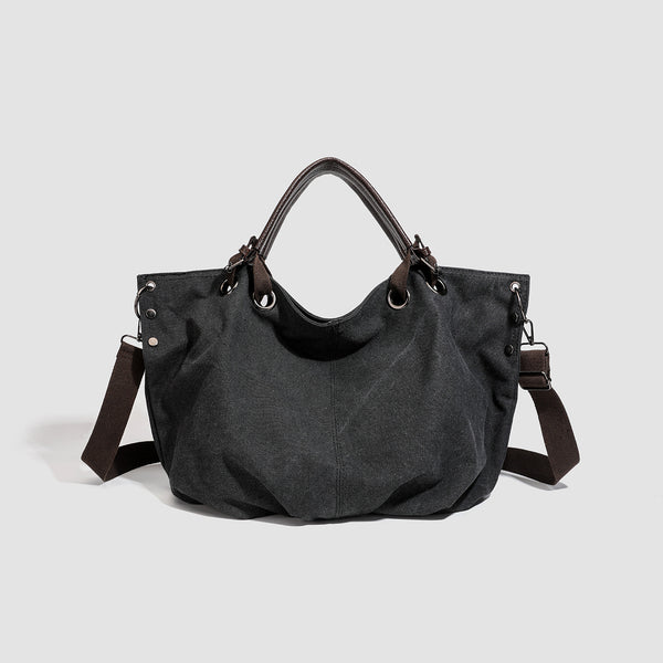 Slouchy matte canvas tote bag with dark dual top handles, metal grommet hardware, and detachable long shoulder strap, detail