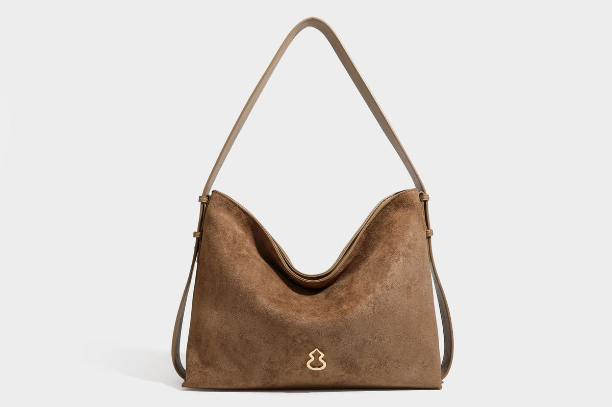 Slouchy suede-finish brown shoulder bag with long single strap and small gold-tone logo emblem on front, detail view 42