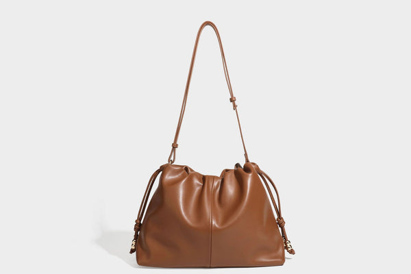 Slouchy ruched drawstring shoulder bag in smooth leather-look finish with gold-tone emblem and slim adjustable strap, detail