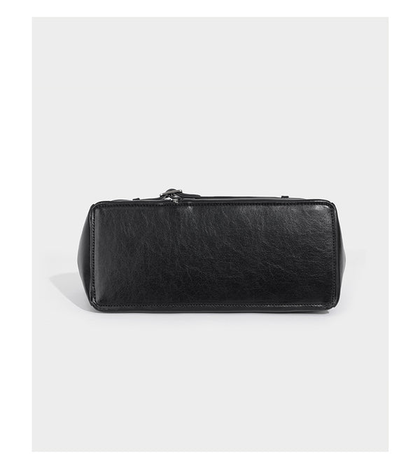 Structured black leather-look satchel bag with silver padlock hardware, front zip pockets, key charms, and top handles