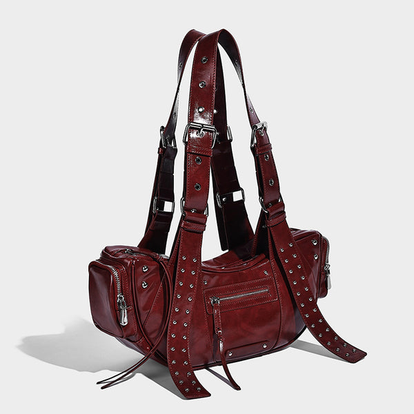 Glossy black crescent shoulder bag with silver-tone rivets, multiple zip pockets, and long adjustable studded straps, detail