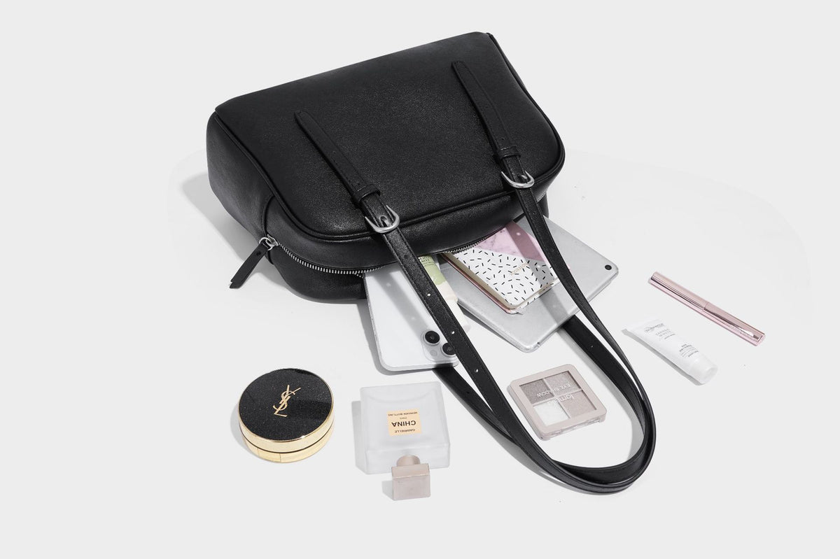 Structured dome-shaped shoulder bag with leather-look finish, top zipper closure, dual adjustable slim straps, and, detail