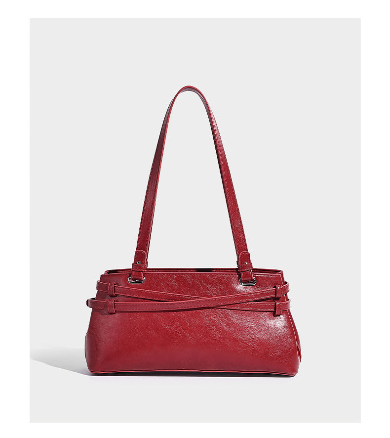 Structured glossy leather-look shoulder bag with wraparound belt straps, silver-tone hardware, and dangling star charm