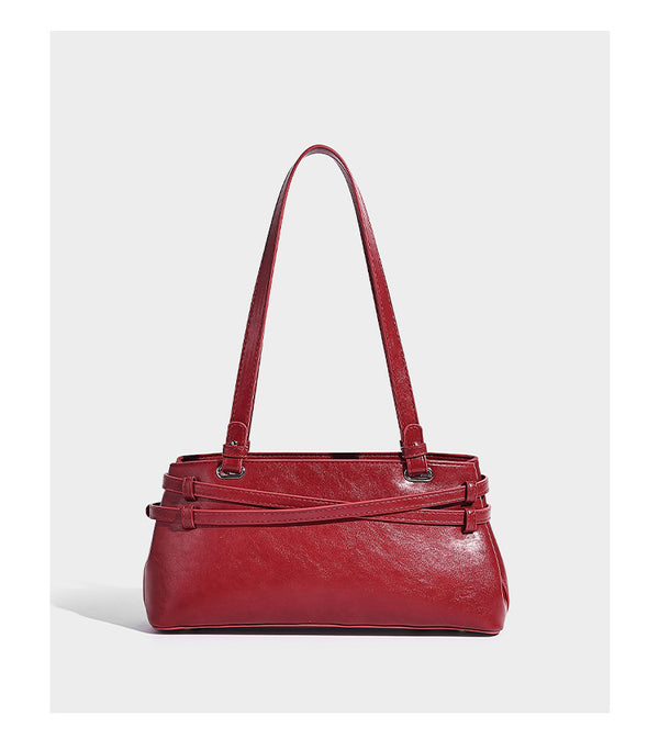 Structured glossy leather-look shoulder bag with wraparound belt straps, silver-tone hardware, and dangling star charm