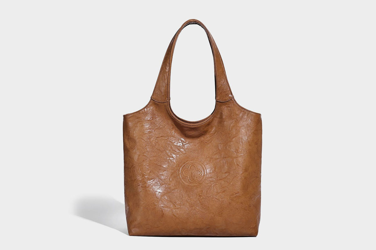Large open-top tote bag with crinkled leather-look finish, long double shoulder straps, and embossed circular detail on