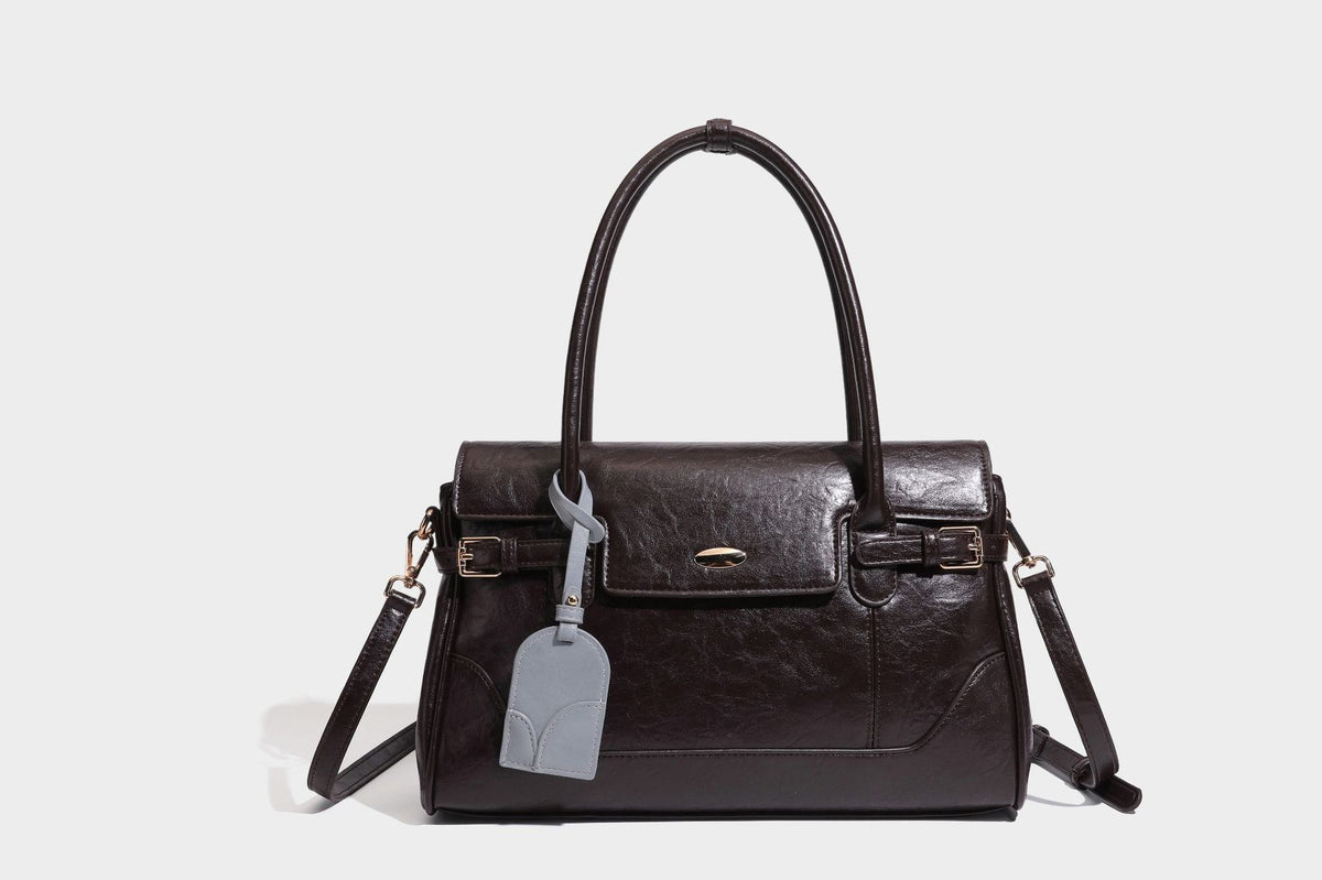 Structured glossy leather-look satchel bag with flap closure, gold-tone buckle accents, double top handles, detachable