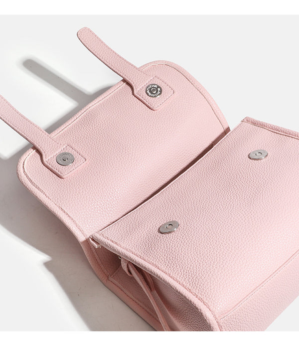 Compact structured flap satchel bag with pebbled texture, snap closure, front strap tabs, and long adjustable crossbody