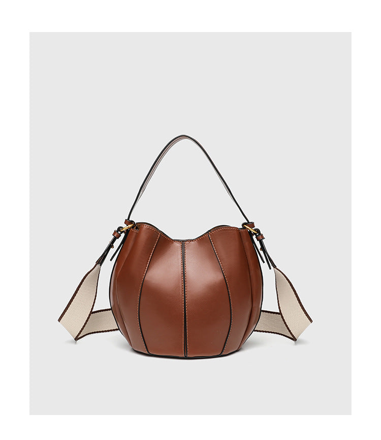 Smooth leather-look paneled bucket bag in brown with wide woven shoulder strap, gold-tone ring hardware, and detachable zip