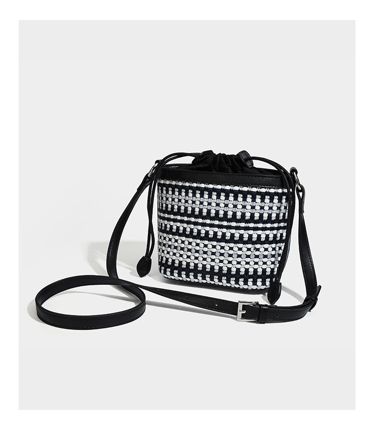 Small structured woven checker bucket bag with braided top handle, drawstring closure, and silver-tone hardware in black