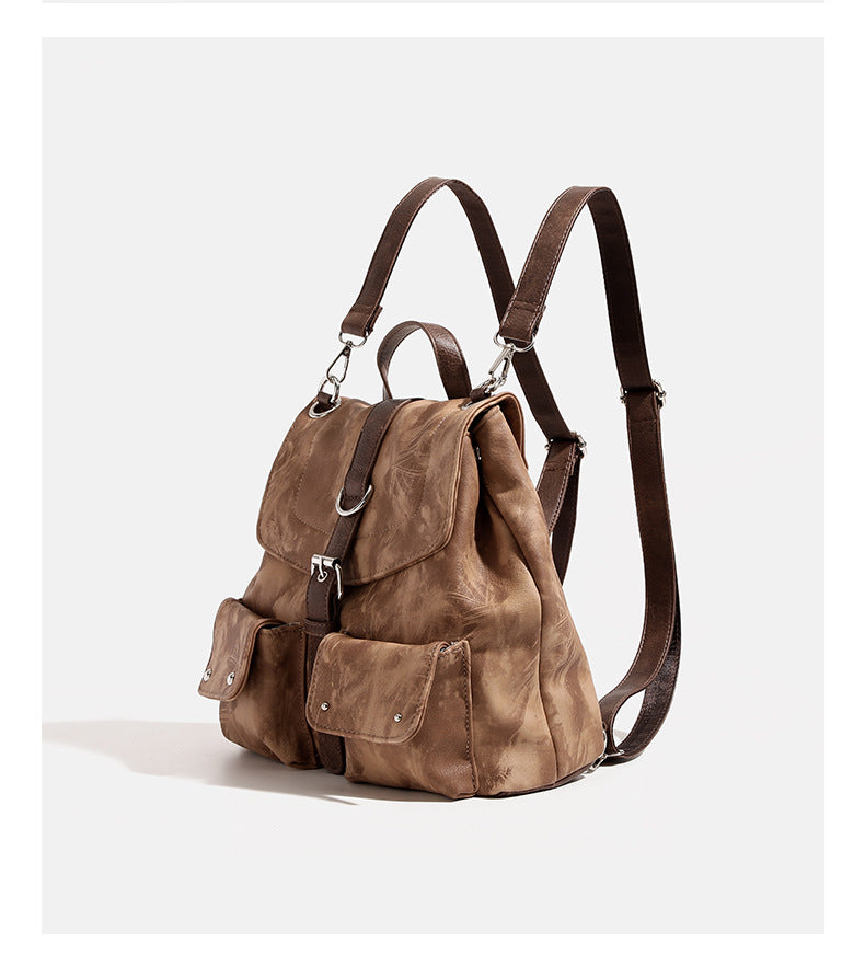 Compact distressed leather-look tan-brown backpack handbag with flap-and-buckle closure, two front patch pockets, top handle