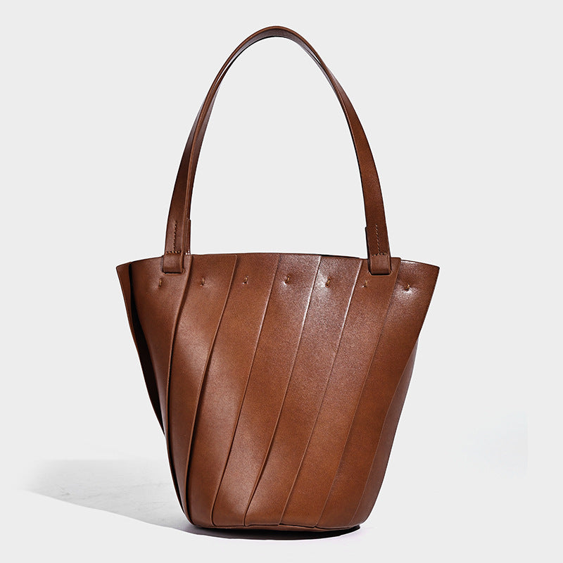 Structured bucket tote bag with vertical panel exterior, dual top handles, and detachable shoulder strap in tan leather-look