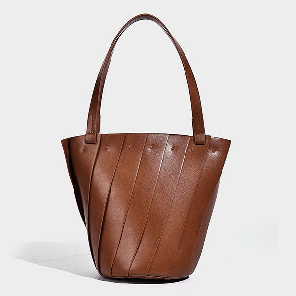 Structured bucket tote bag with vertical panel exterior, dual top handles, and detachable shoulder strap in tan leather-look