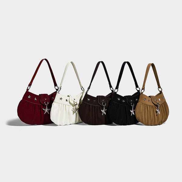 Ruched shoulder bag with curved flap, silver star studs, dangling starfish charm, and adjustable crossbody strap, detail view