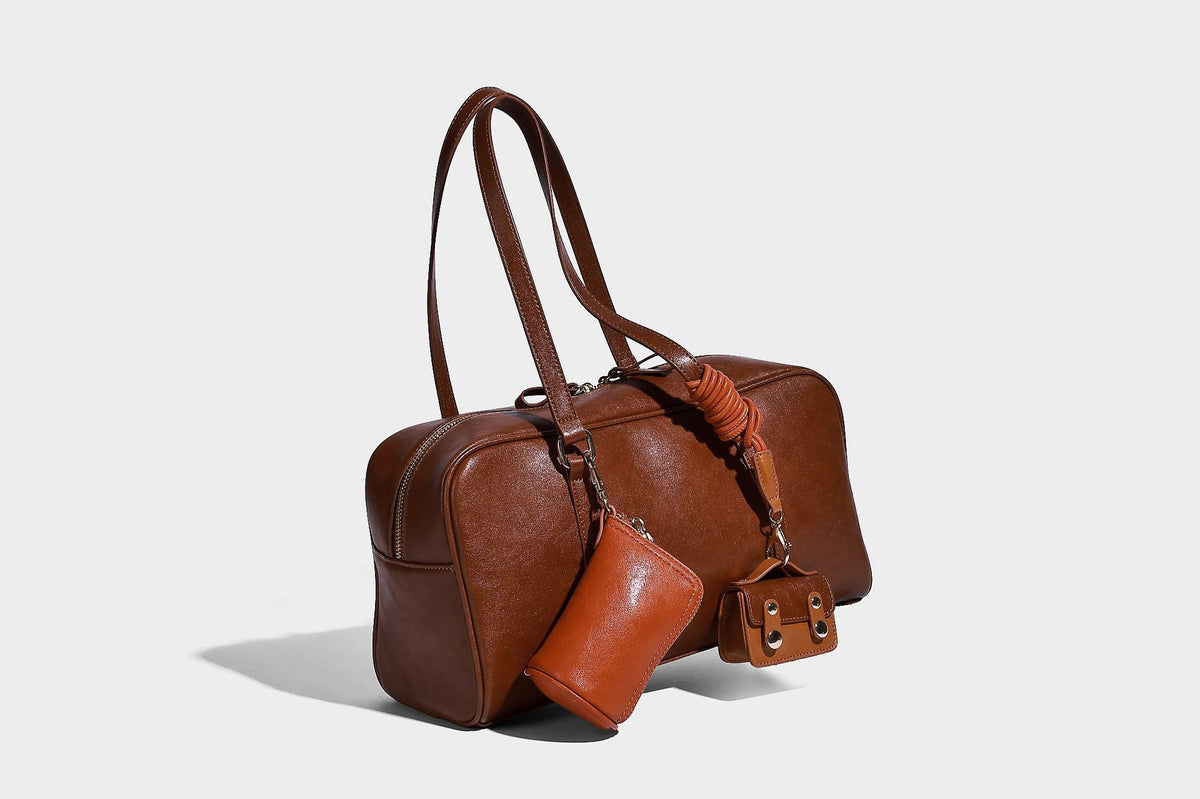 Strukturierte Boston-Schultertasche in glänzender Lederoptik mit zwei langen Trageriemen, Reißverschluss oben, goldfarbenen Beschlägen und zwei