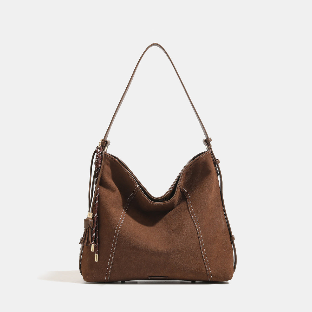 Slouchy suede-finish hobo shoulder bag in warm mocha brown with contrast stitching, braided tassel side accent, and, detail