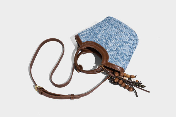 Blaue gewebte Bucket-Bag in Denim-Optik mit Besatz in brauner Lederoptik, rundem Henkel, Quastenanhänger mit Holzperlen und verstellbarem