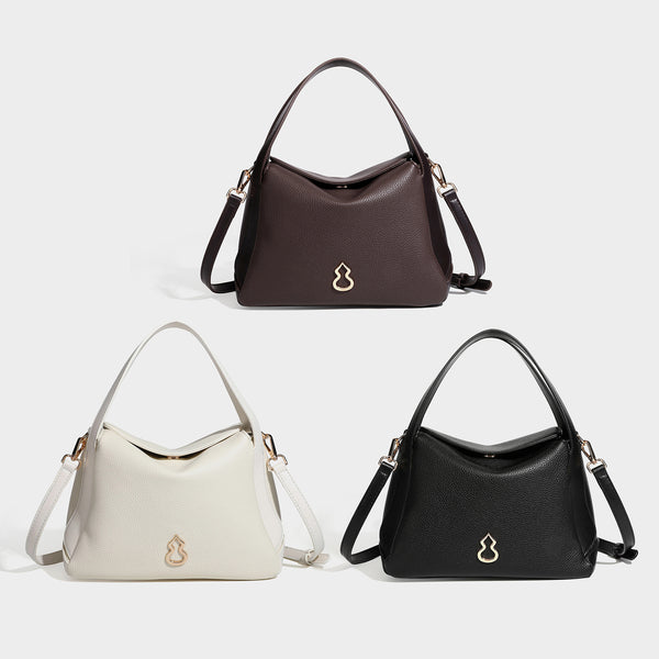 Structured pebbled leather-look shoulder bag with flap top, gold-tone emblem hardware, dual top handles, and detachable