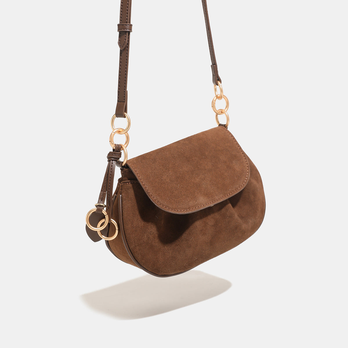 Small rounded flap crossbody saddle bag with gold-tone ring hardware and adjustable strap, detail view 3