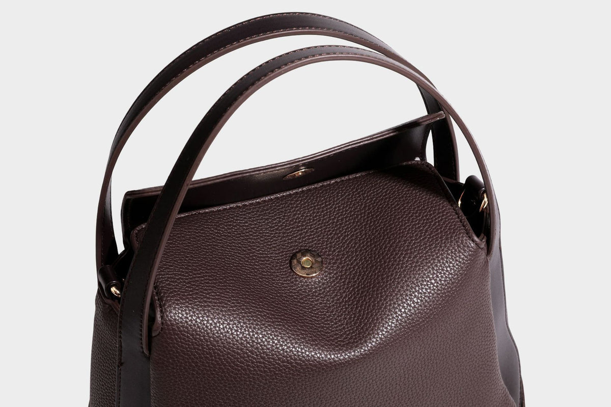 Structured pebbled leather-look shoulder bag with flap top, gold-tone emblem hardware, dual top handles, and detachable