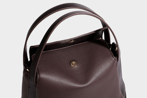 Structured pebbled leather-look shoulder bag with flap top, gold-tone emblem hardware, dual top handles, and detachable