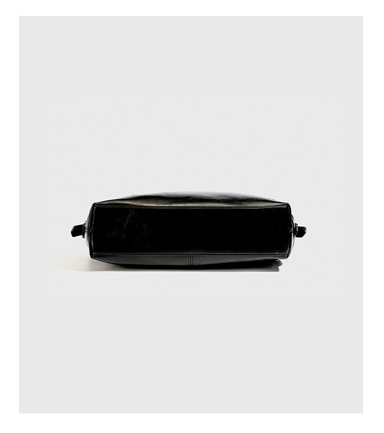 Slouchy hobo shoulder bag with glossy leather-look finish, silver-tone chain drape across front, side buckle pockets, and