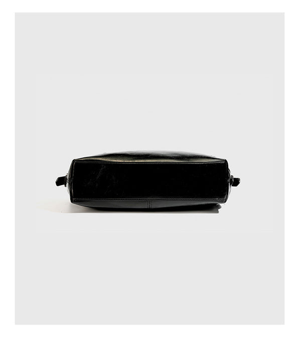 Slouchy hobo shoulder bag with glossy leather-look finish, silver-tone chain drape across front, side buckle pockets, and