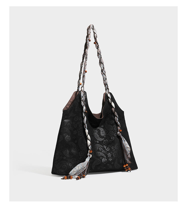 Slouchy paisley-embossed suede-look shoulder tote bag with braided patterned fabric straps and wood bead accents, detail view