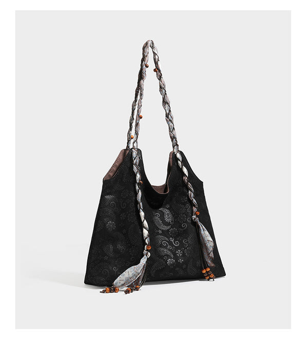Slouchy paisley-embossed suede-look shoulder tote bag with braided patterned fabric straps and wood bead accents, detail view