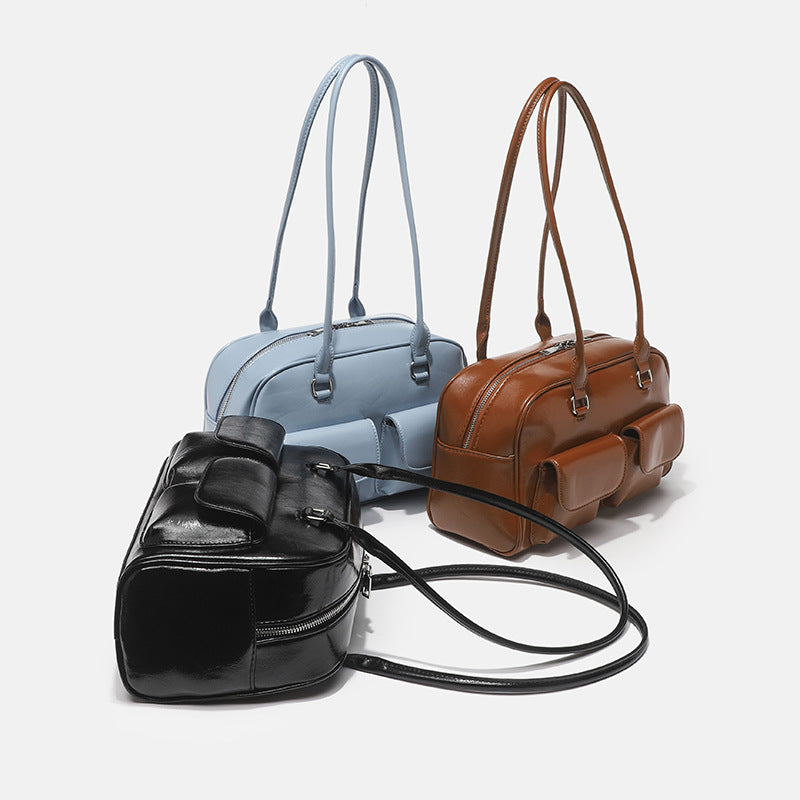 Structured glossy leather-look bowling shoulder bag with two front flap pockets, top zip closure, and long double shoulder