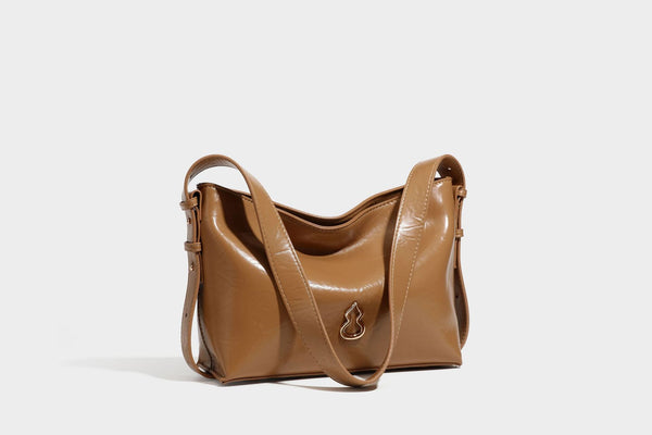 Lässig fallende Hobo-Schultertasche mit offenem Oberteil aus glänzender, karamellbrauner Lederoptik, mit Logo-Beschlägen in Goldoptik und langem, verstellbarem