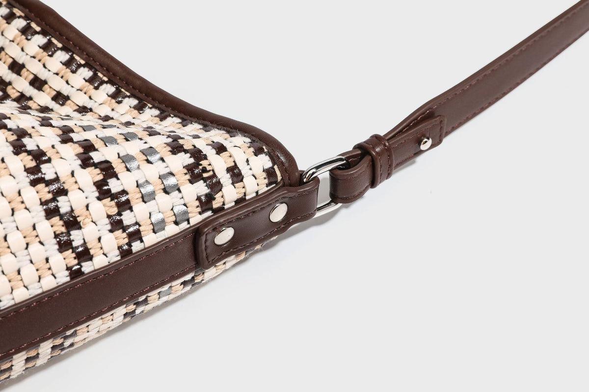 Woven stripe bucket shoulder bag in cream and dark brown with leather-look trim, knotted adjustable strap, and small shield