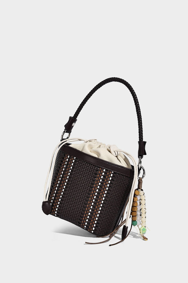 Small woven bucket bag with drawstring top, braided handle, detachable crossbody strap, and silver-tone ring hardware, detail