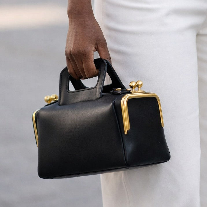 Compact dark brown leather-look top-handle bag with gold-tone ball-tip frame hardware and detachable adjustable crossbody