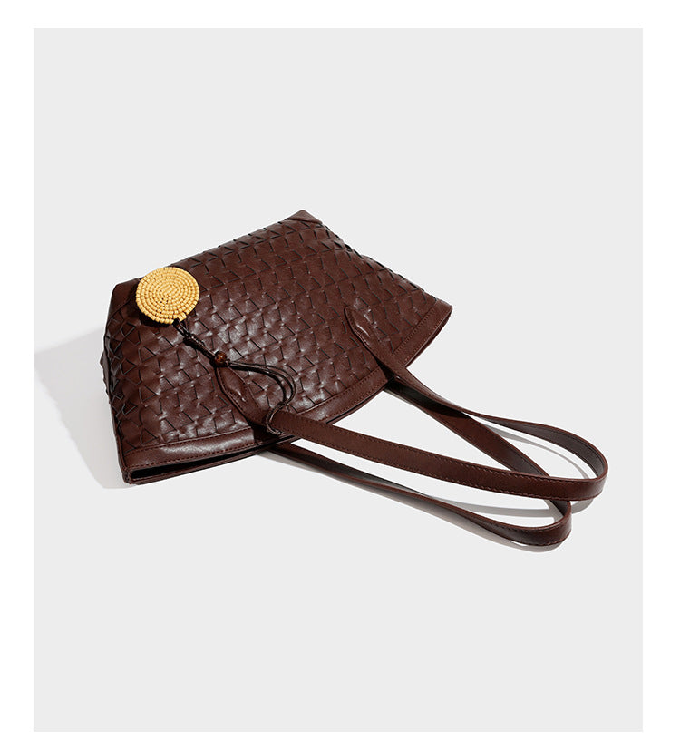 Large leather-look tote bag with geometric woven emboss, double shoulder straps, and round woven cord charm in brown, detail