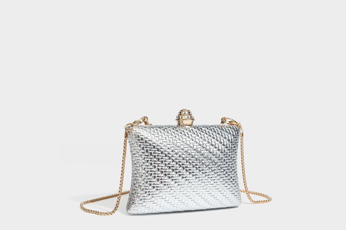 Small structured rectangular metallic woven-texture clutch bag with jeweled knob clasp and gold-tone chain strap, detail view