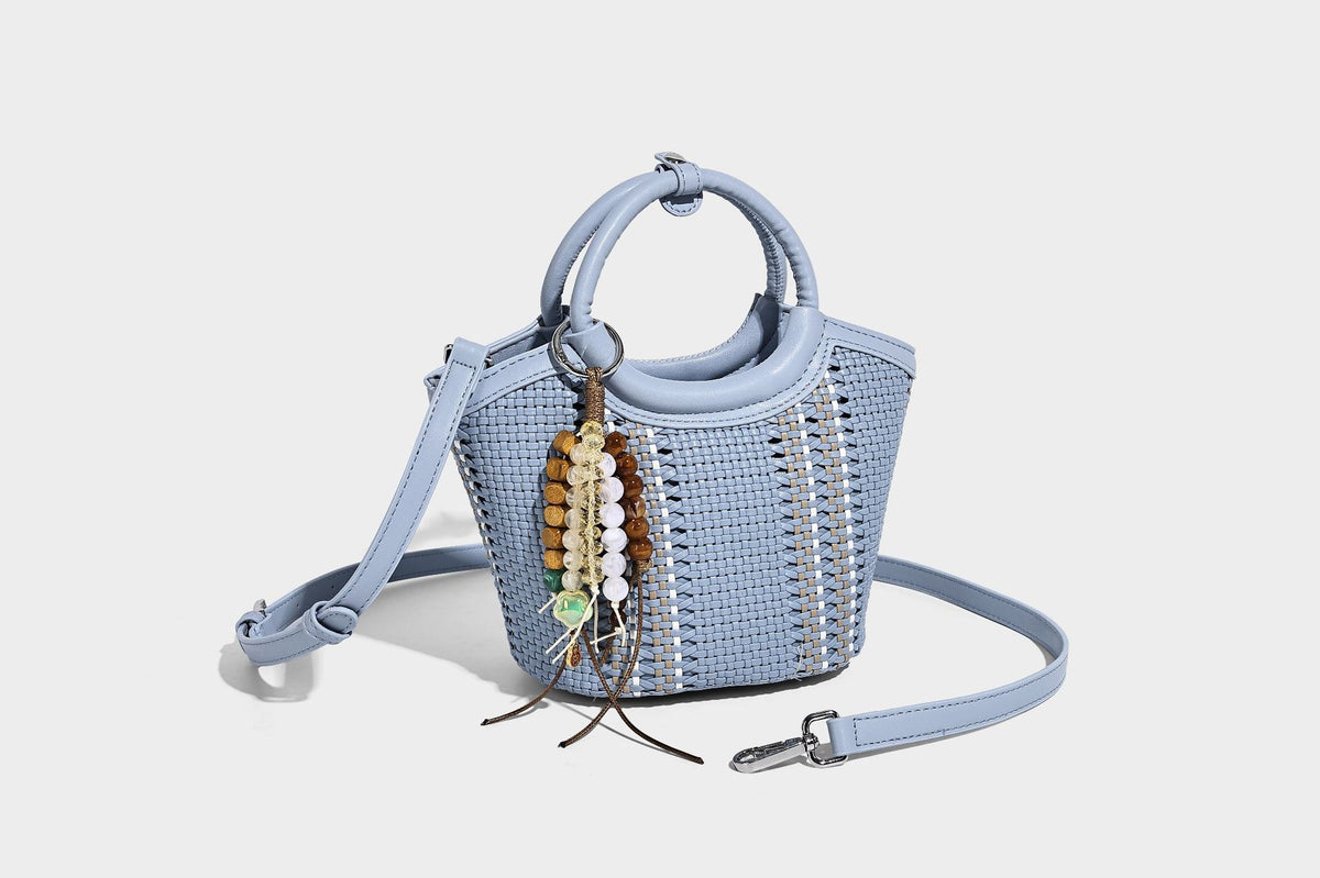 Kleine strukturierte Beuteltasche aus geflochtenem Material mit rundem Tragegriff in Lederoptik, silberfarbenen Beschlägen und perlenbesetztem Quastenanhänger, Detail