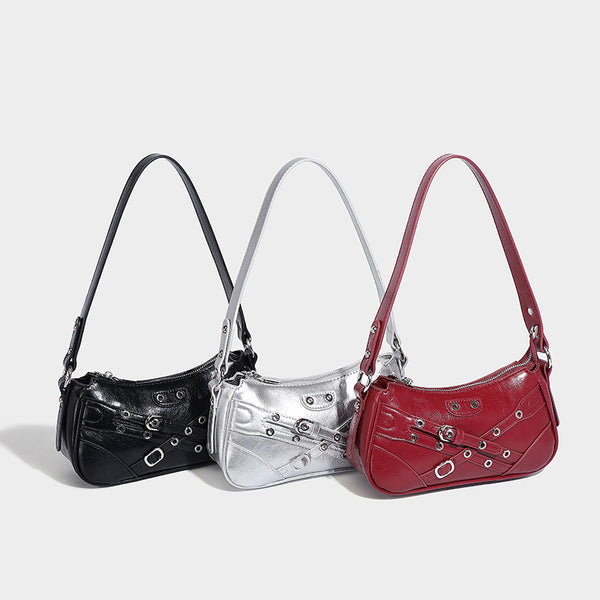 Compact moto-inspired shoulder bag with crisscross grommet strap detail, glossy textured finish, and adjustable crossbody
