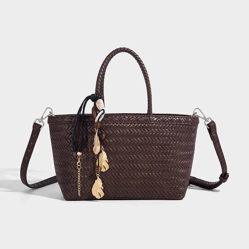 Structured chevron woven leather-look tote bag with braided top handles, gold feather charm, and adjustable shoulder strap