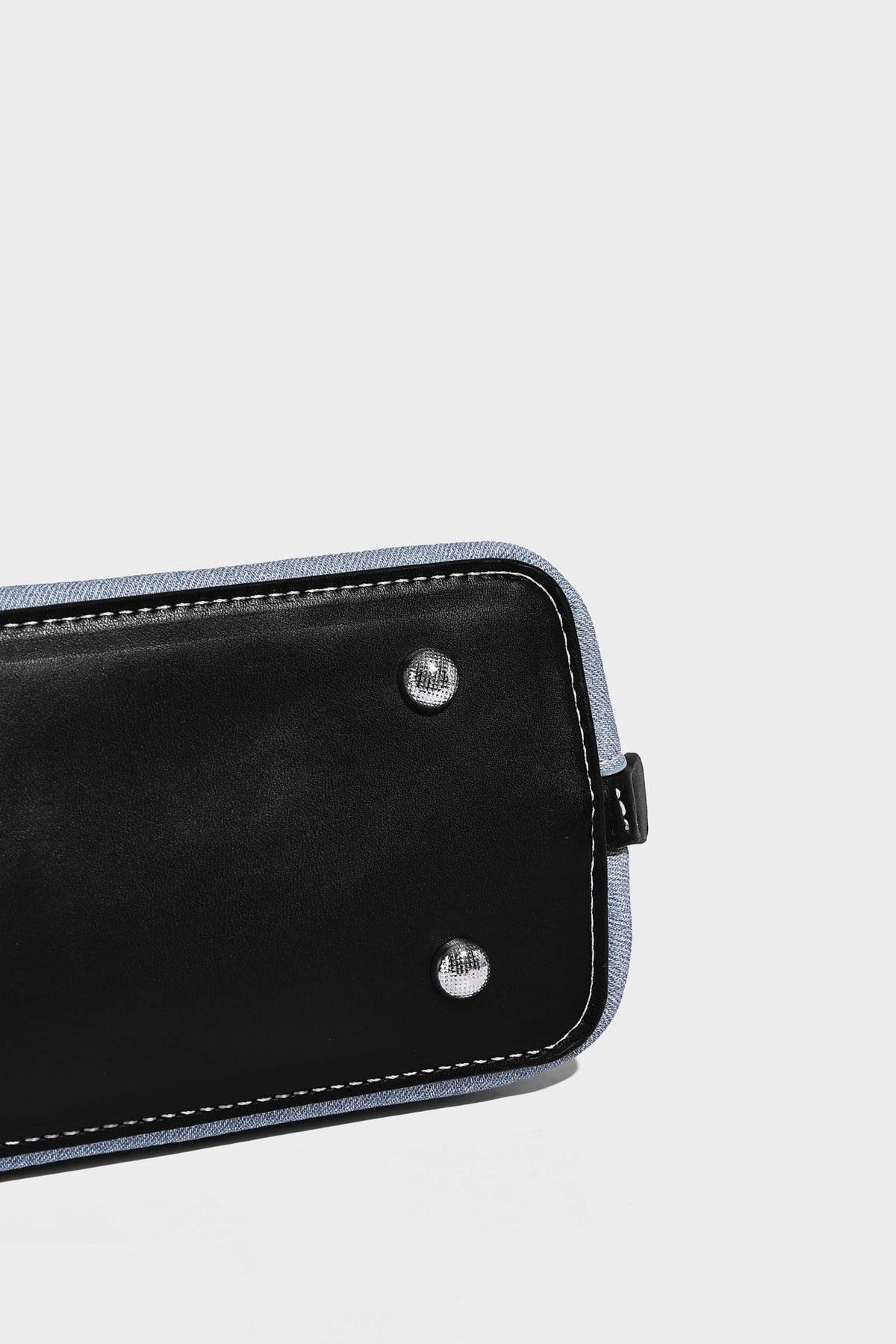 Compact structured satchel in light blue denim-look fabric with black leather-look trim, silver turn-lock closure, rolled