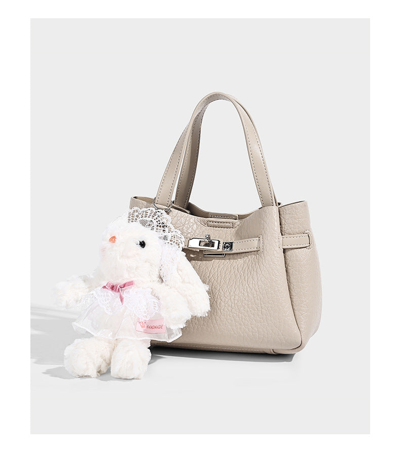 Small structured pebbled bucket tote with double top handles, silver turn-lock hardware, and detachable shoulder strap