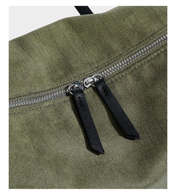 Olivgrüne Schultertasche in Zylinderform aus Canvas mit Riemen in schwarzer Lederoptik, Reißverschluss oben und silberfarbenen Beschlägen, Detailansicht