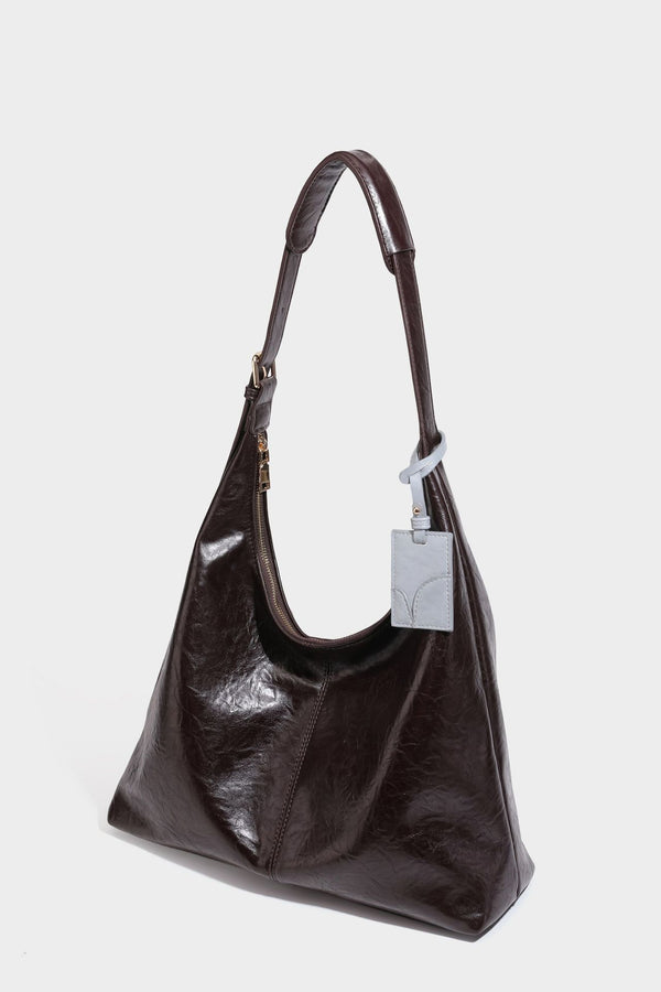 Große dunkelbraune, glänzende, geknautschte Hobo-Schultertasche mit Reißverschluss, goldfarbenen Metalldetails, verstellbarem Trageriemen und Hellblau