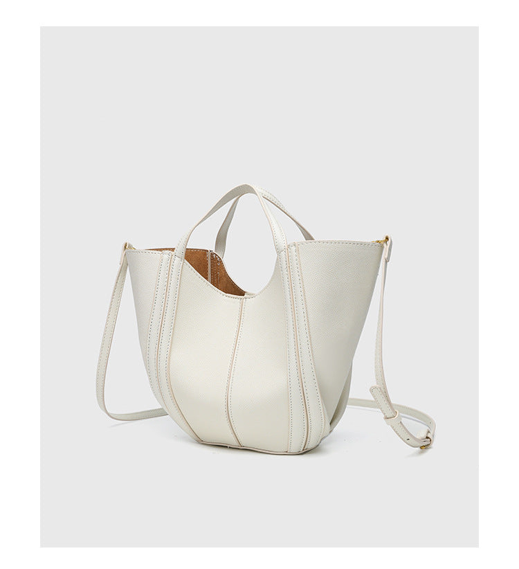 Structured open-top tote bag in tan brown pebbled leather-look finish with vertical seam accents, black edge piping, curved